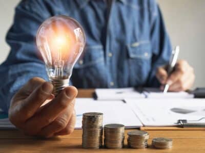 Business man holding light bulb and some coins on table writing saving bank and account for his money all in finance accounting concept.