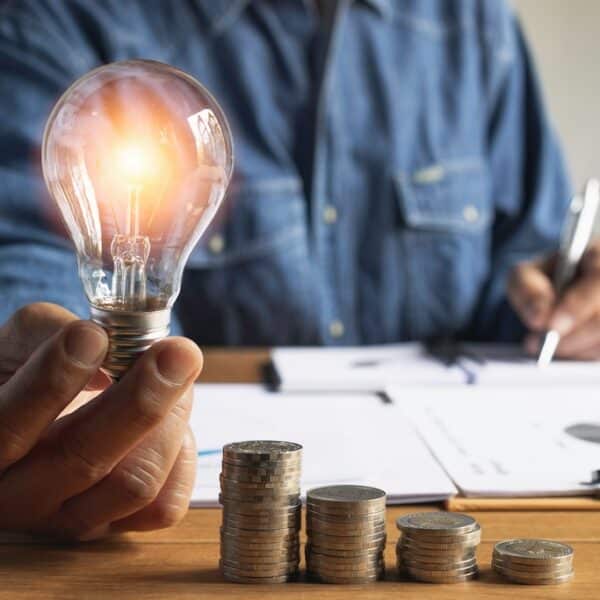 Business man holding light bulb and some coins on table writing saving bank and account for his money all in finance accounting concept.
