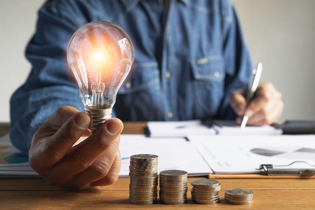 Business man holding light bulb and some coins on table writing saving bank and account for his money all in finance accounting concept.