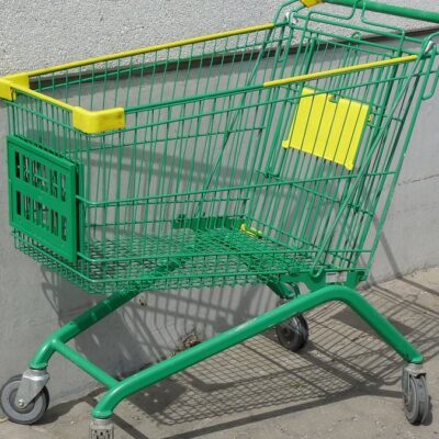 Prázdný zelený nákupní vozík u šedé zdi před supermarketem