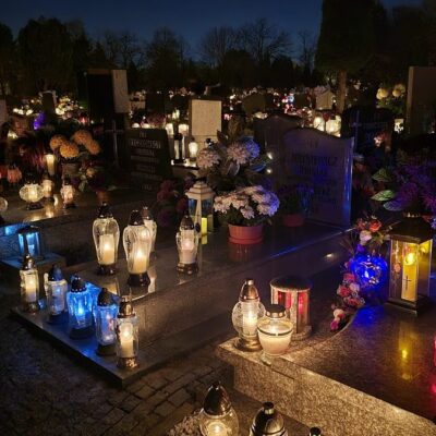 Hroby na hřbitově večer o Dušičkách ozářené desítkami svíček v lucernách