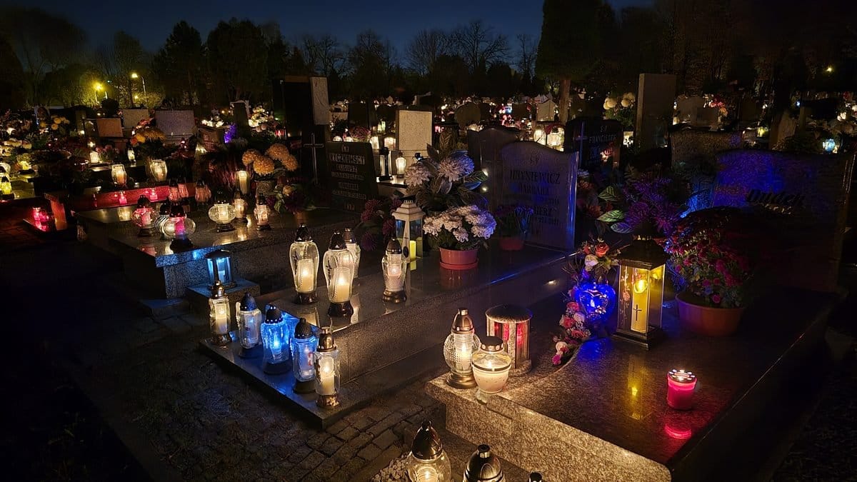 Hroby na hřbitově večer o Dušičkách ozářené desítkami svíček v lucernách