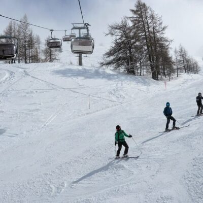 Lyžaři na sjezdovce pod sedačkovou lanovkou