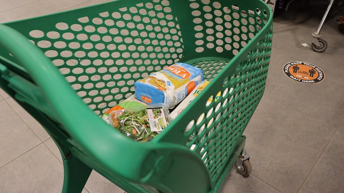 Nákupní vozík s potravinami v uličce supermarketu