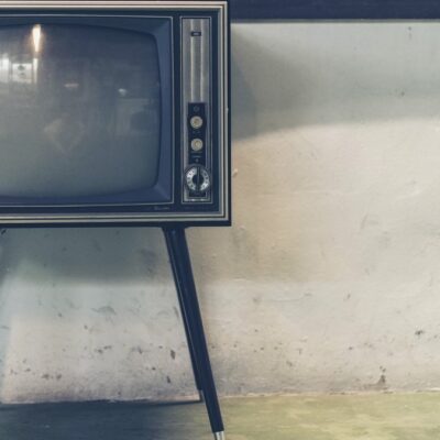 Starý televizor na tenkých nohách stojí u oprýskané zdi