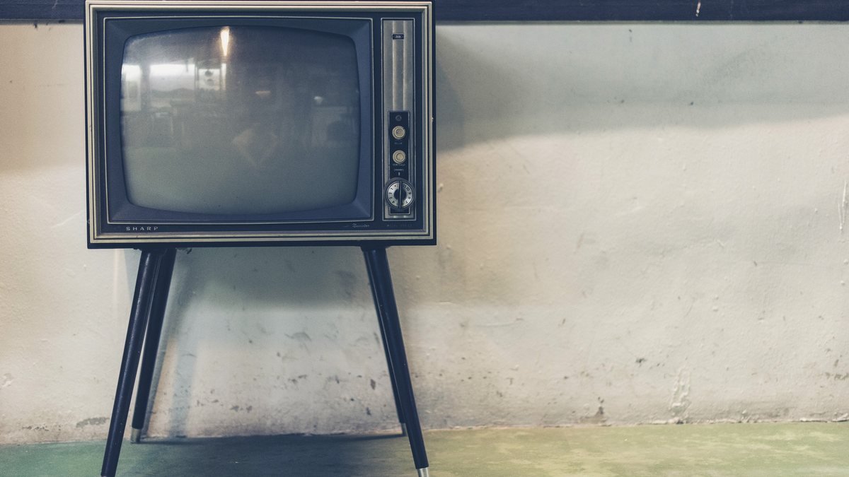 Starý televizor na tenkých nohách stojí u oprýskané zdi
